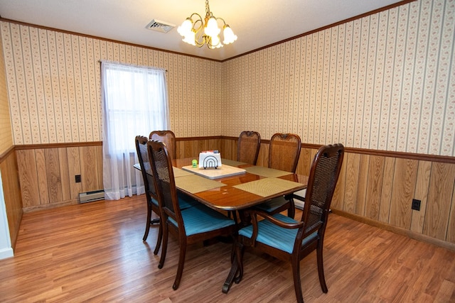 22170 Barnes Cir, Parksley, VA 23421 - dining space with a chandelier, baseboard heating, ornamental molding, a wainscoted wall, and light wood-style flooring