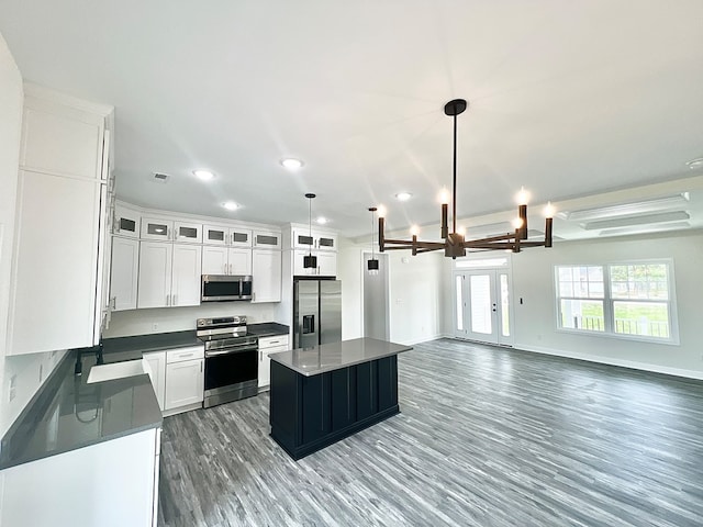 27212 Castle Row, Cape Charles, VA 23310 - kitchen featuring stainless steel appliances, dark countertops, light wood-style flooring, white cabinets, and a center island