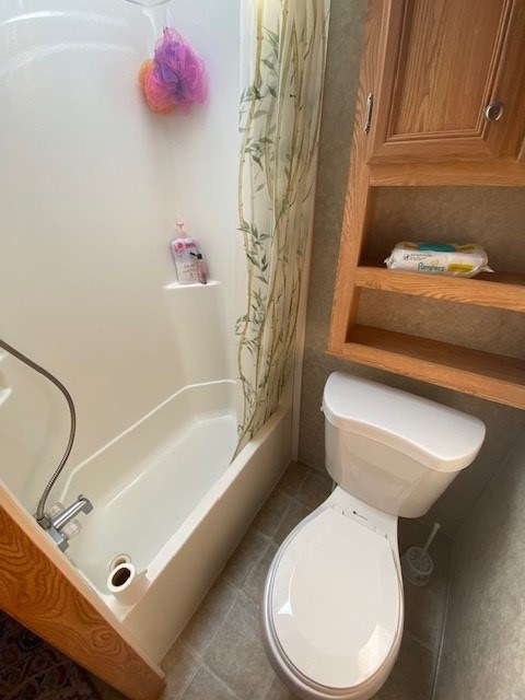 bathroom with toilet and shower / bath combo with shower curtain