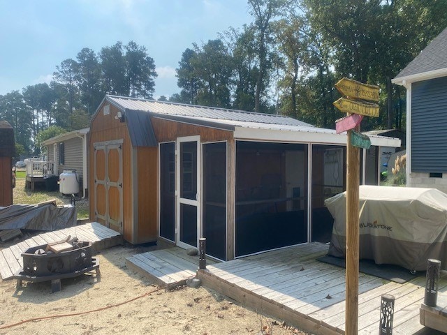 rear view of property featuring a sunroom and a storage unit