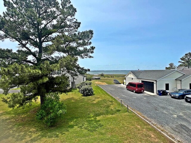 5061 Bay Colony Ln, Chincoteague, VA 23336 - view of green lawn featuring gravel driveway, an attached garage, and a water view