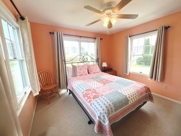 5061 Bay Colony Ln, Chincoteague, VA 23336 - carpeted bedroom featuring multiple windows, baseboards, and ceiling fan