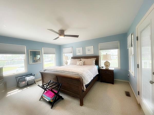 5061 Bay Colony Ln, Chincoteague, VA 23336 - bedroom with multiple windows, light colored carpet, baseboards, and ceiling fan