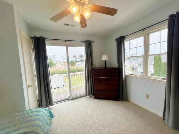5061 Bay Colony Ln, Chincoteague, VA 23336 - carpeted bedroom with access to outside, multiple windows, baseboards, and ceiling fan