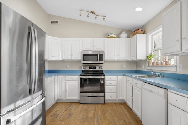 kitchen featuring sink, vaulted ceiling, light wood-type flooring, white cabinetry, and stainless steel appliances