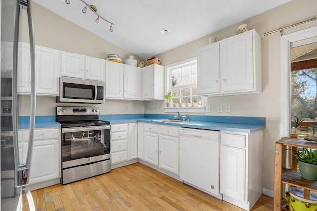 kitchen with stainless steel appliances, white cabinetry, lofted ceiling, and sink