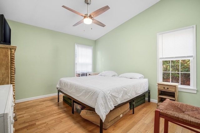 bedroom featuring multiple windows, ceiling fan, lofted ceiling, and light wood-type flooring