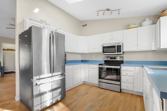 kitchen featuring white cabinetry, ceiling fan, stainless steel appliances, light hardwood / wood-style floors, and lofted ceiling