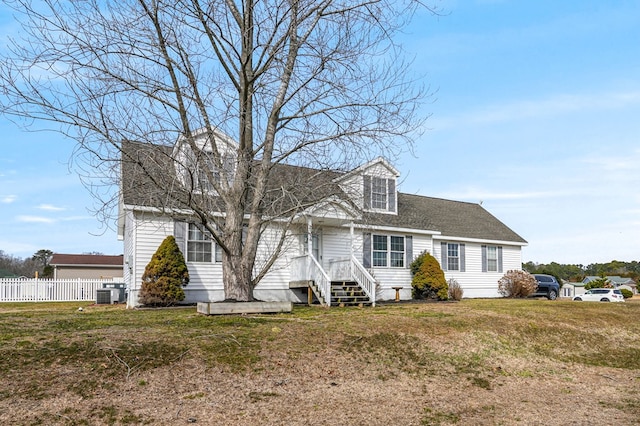 cape cod-style house with a shingled roof, a front yard, fence, and central air condition unit