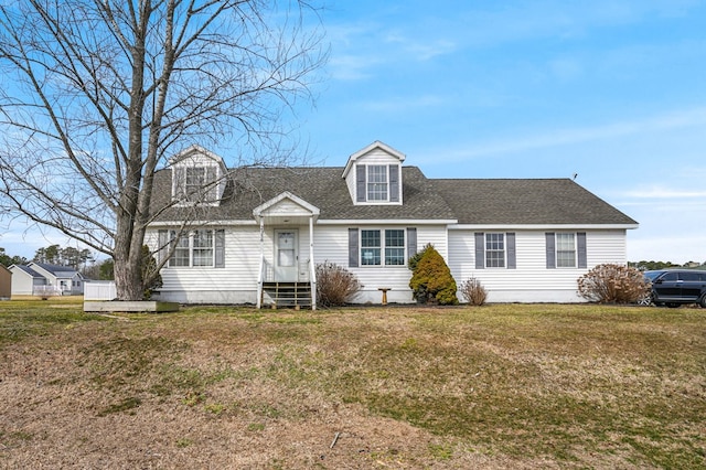 cape cod-style house with entry steps, a shingled roof, and a front yard