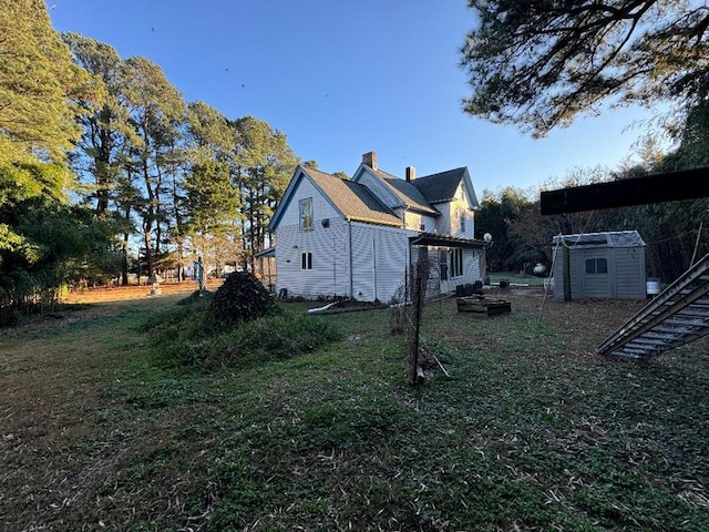 view of side of property featuring a lawn and a storage unit