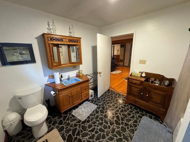 bathroom with vanity, toilet, and a wood stove