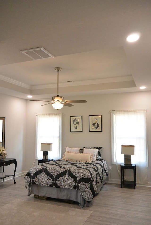 bedroom featuring a tray ceiling, ceiling fan, light wood-type flooring, and ornamental molding