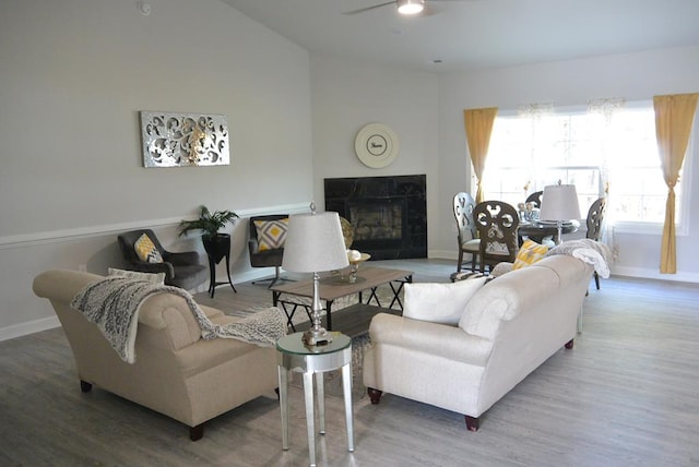 living room featuring ceiling fan, wood-type flooring, and a high end fireplace