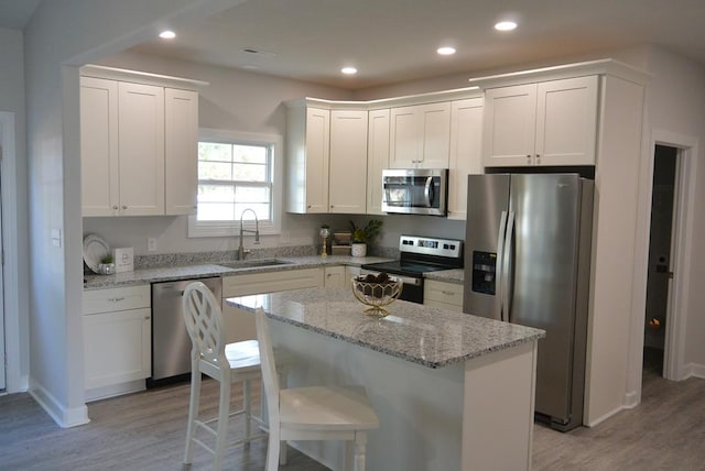 kitchen featuring a center island, sink, light wood-type flooring, white cabinetry, and stainless steel appliances