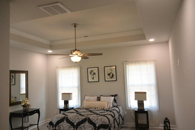 bedroom featuring a raised ceiling, multiple windows, and ceiling fan