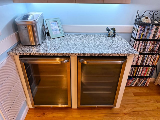 room details featuring light stone countertops, beverage cooler, and light hardwood / wood-style floors