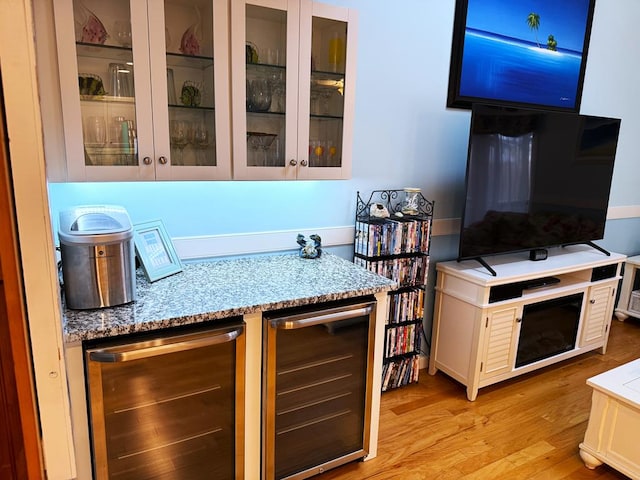 bar featuring wine cooler, light stone countertops, white cabinetry, and light hardwood / wood-style floors