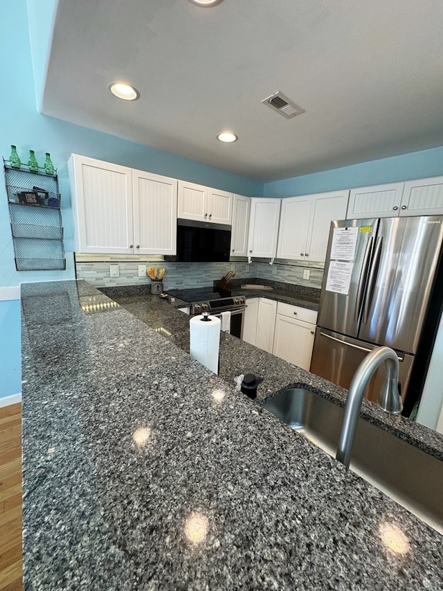 kitchen with dark stone countertops, appliances with stainless steel finishes, and white cabinets