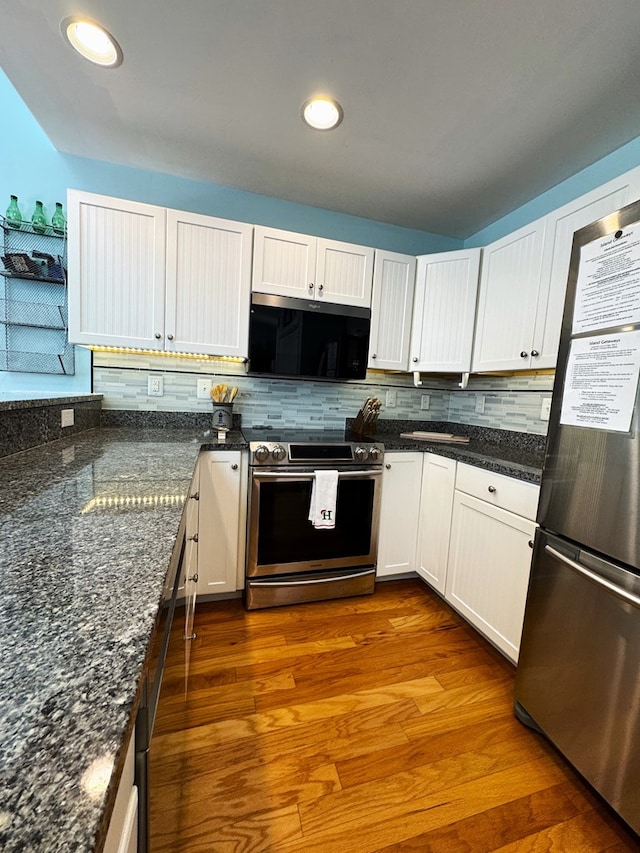 kitchen with appliances with stainless steel finishes, dark stone counters, and white cabinets