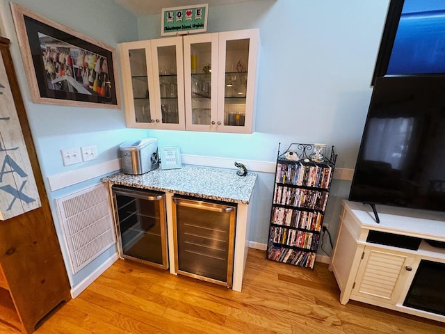 bar featuring white cabinetry, light stone countertops, wine cooler, and light hardwood / wood-style floors