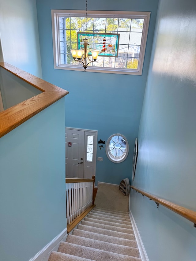 stairway with an inviting chandelier, carpet floors, and a high ceiling