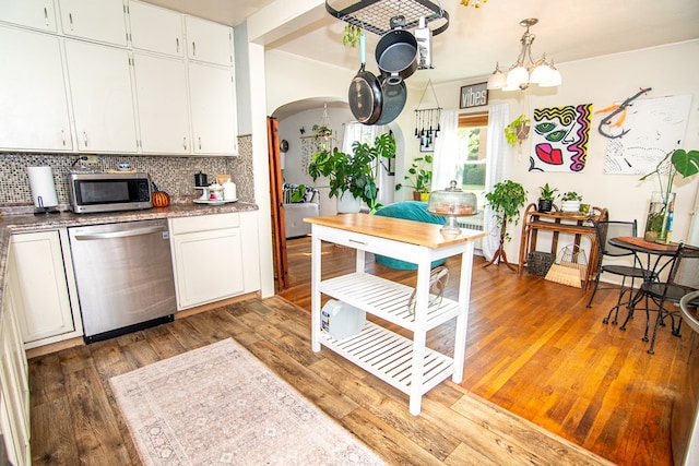 kitchen with white cabinetry, backsplash, light wood-type flooring, and appliances with stainless steel finishes