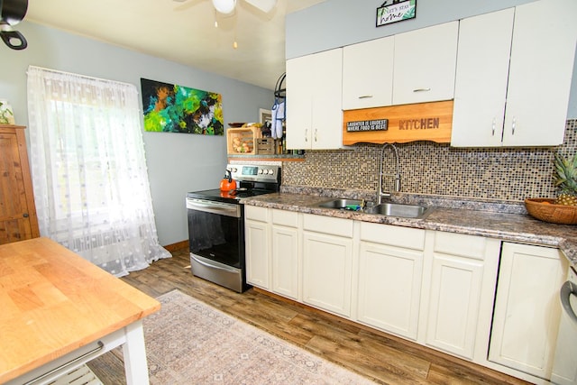 kitchen featuring light wood-style floors, ceiling fan, tasteful backsplash, a sink, and stainless steel electric range