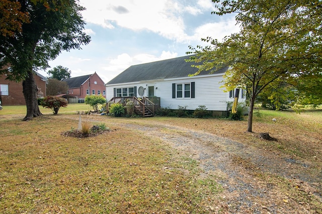 view of front of house featuring roof with shingles, driveway, and a front lawn