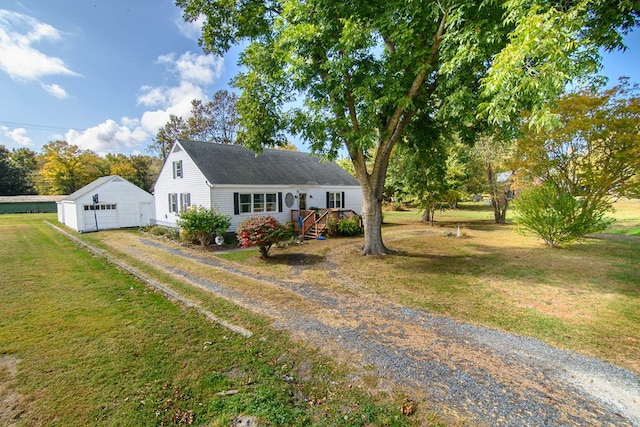 view of front of house with an outbuilding, a detached garage, a front lawn, and driveway