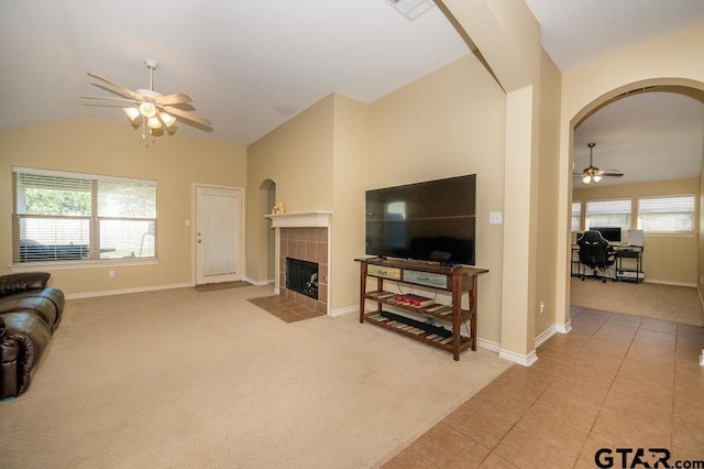 11017 Westhaven Cir, Flint, TX 75762 - carpeted living area with a ceiling fan, arched walkways, lofted ceiling, a tiled fireplace, and tile patterned floors