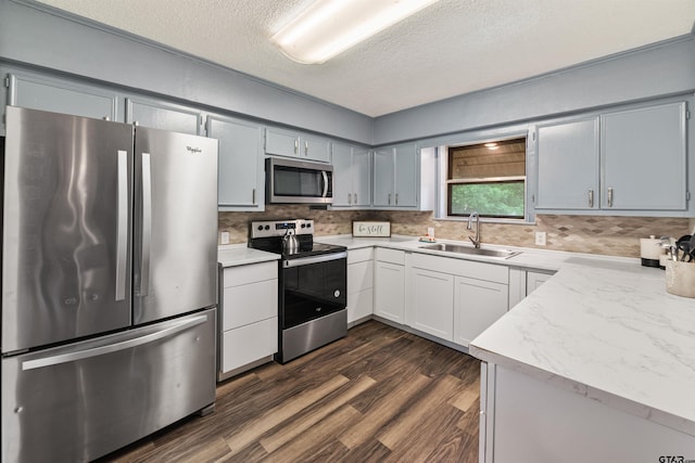 kitchen featuring tasteful backsplash, a textured ceiling, stainless steel appliances, sink, and dark hardwood / wood-style floors