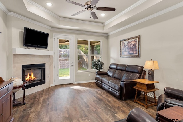 living room featuring a raised ceiling, ornamental molding, and dark hardwood / wood-style floors