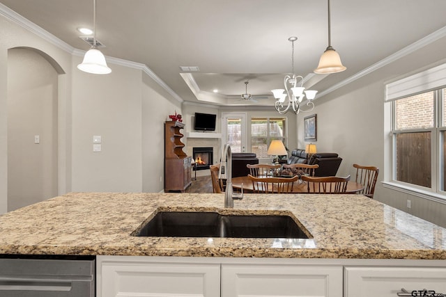 kitchen with white cabinets, hanging light fixtures, sink, and light stone counters