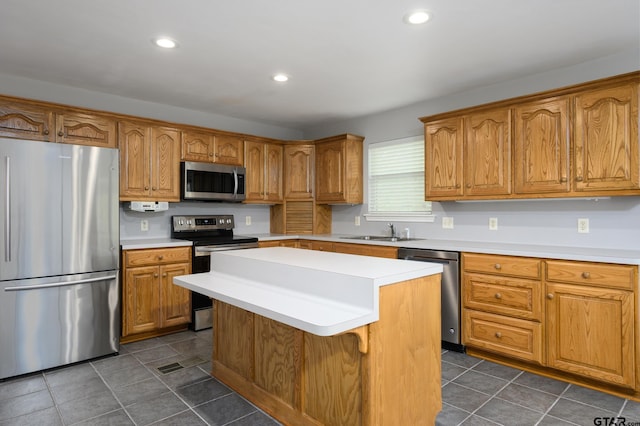 kitchen with light countertops, a sink, a kitchen island, and appliances with stainless steel finishes