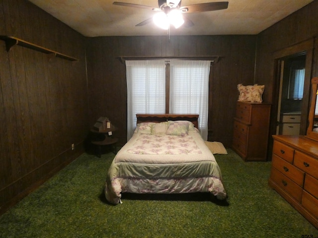 bedroom with dark carpet, ceiling fan, and wood walls