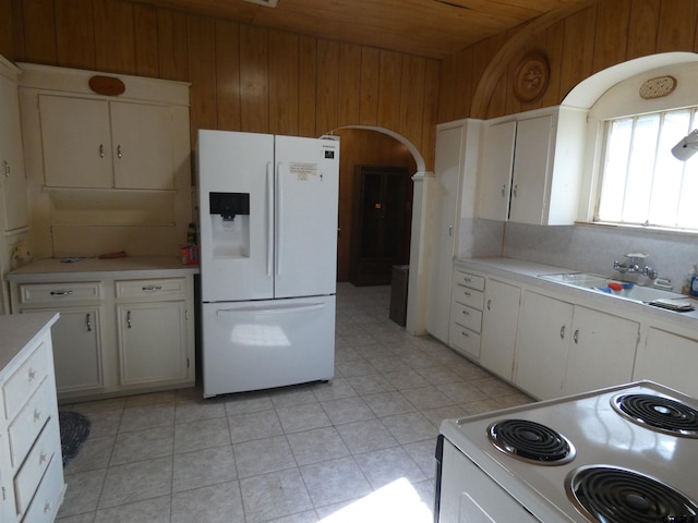 kitchen featuring white appliances, sink, wooden ceiling, white cabinets, and wood walls