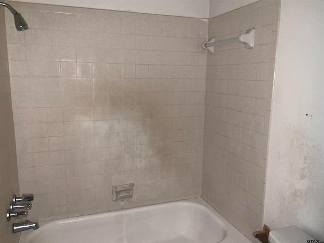 bathroom featuring tiled shower / bath combo and toilet