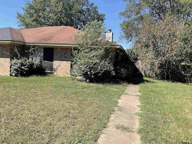 8307 Garrett Dr, Tyler, TX 75703 - view of side of home featuring a yard, brick siding, and a chimney