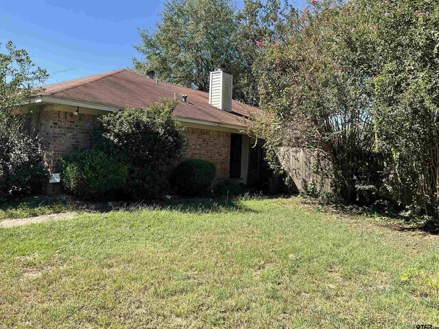 8307 Garrett Dr, Tyler, TX 75703 - view of side of property with brick siding, a yard, and a chimney