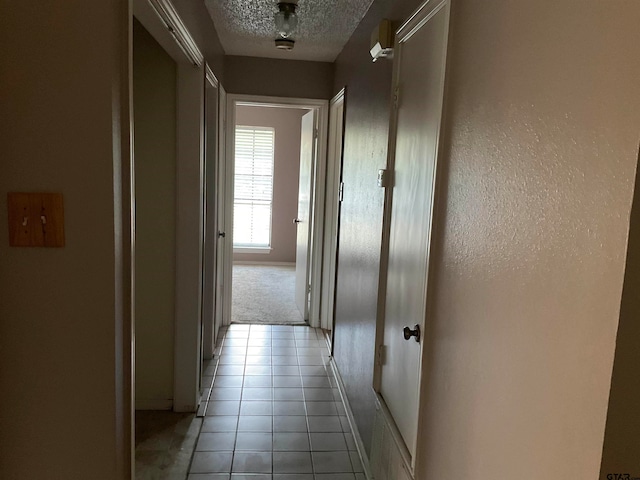 hallway featuring a textured ceiling and light tile patterned floors