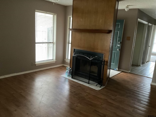 8307 Garrett Dr, Tyler, TX 75703 - unfurnished living room featuring plenty of natural light, wood finished floors, and a fireplace with flush hearth