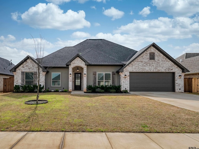 french provincial home with fence, driveway, a front lawn, a garage, and brick siding