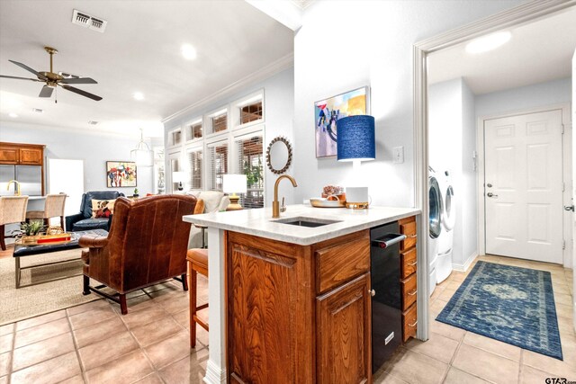 kitchen with appliances with stainless steel finishes, crown molding, kitchen peninsula, light tile patterned floors, and sink