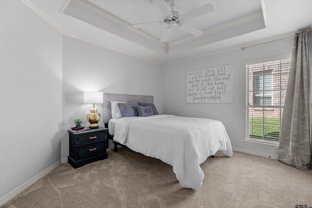 carpeted bedroom featuring ceiling fan, ornamental molding, multiple windows, and a tray ceiling