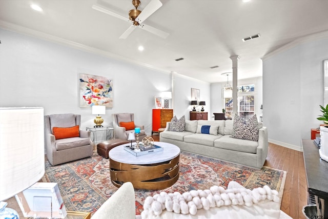 living room featuring hardwood / wood-style flooring, crown molding, and ornate columns