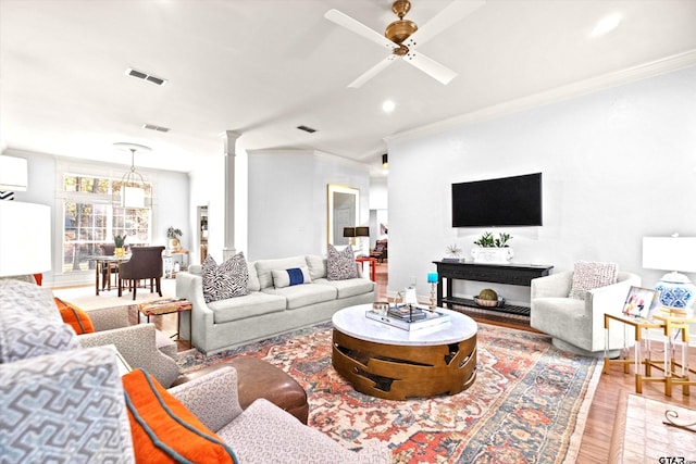 living room with decorative columns, crown molding, ceiling fan, and light hardwood / wood-style floors