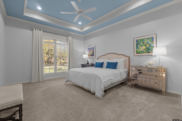 carpeted bedroom featuring ceiling fan, a tray ceiling, and ornamental molding