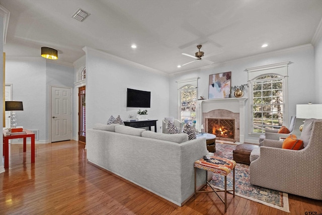 living room with a high end fireplace, ceiling fan, ornamental molding, and hardwood / wood-style floors