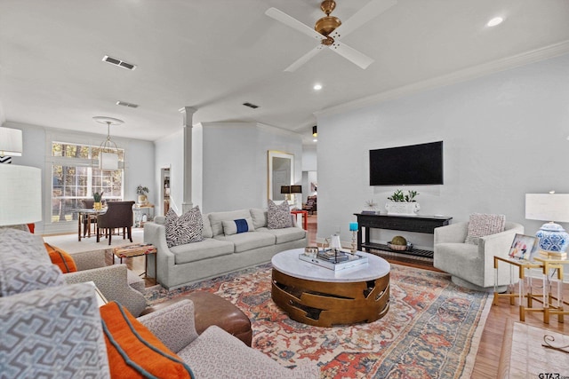 living room with hardwood / wood-style flooring, ceiling fan, and ornamental molding